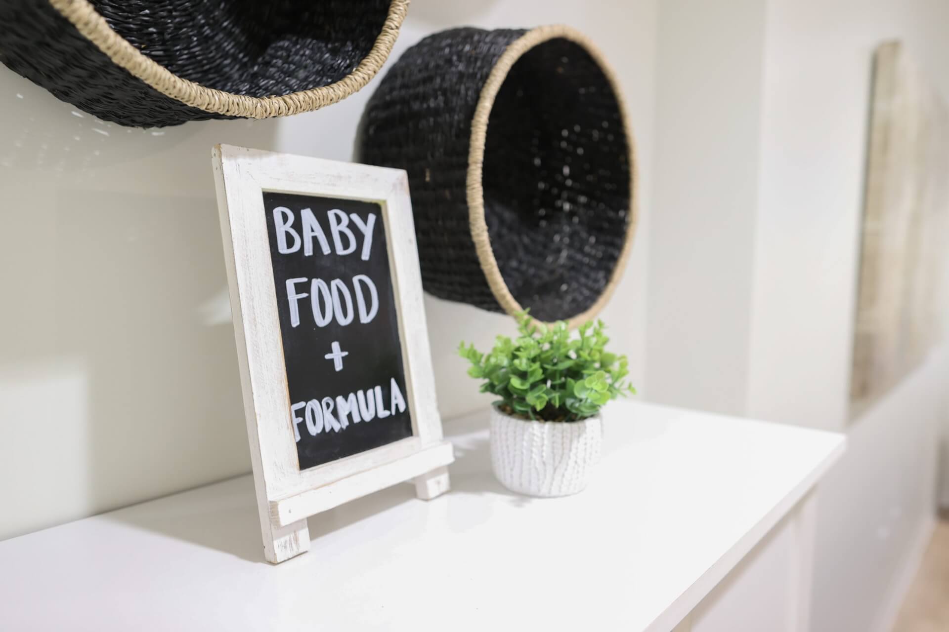 Baby Food and Formula sign next to two hanging baskets and a plant