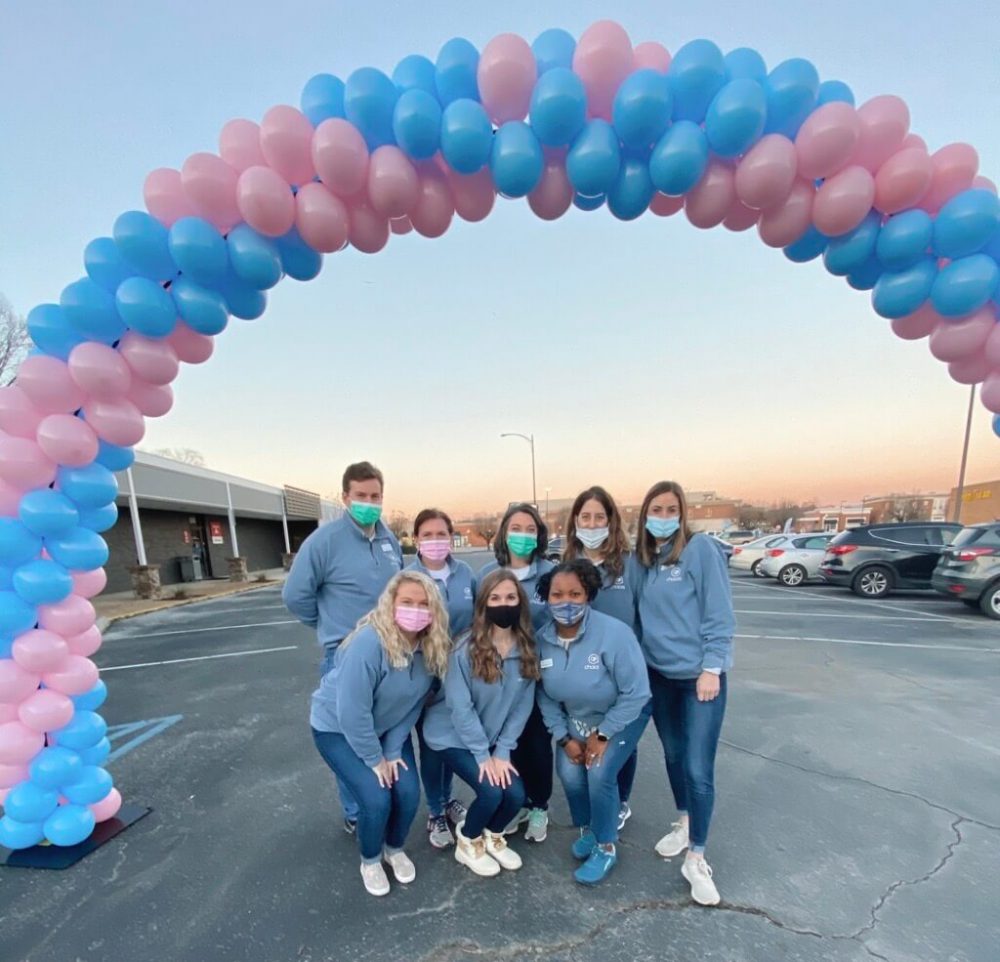 2021 Baby Shower Choices Chattanooga team standing beneath an arch of blue and pink balloons